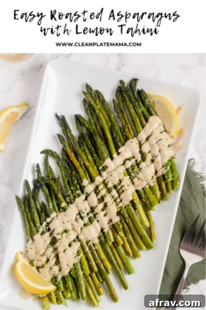 Easy Roasted Asparagus with Creamy Lemon Tahini Sauce 7 A large platter of roasted asparagus spears topped with creamy lemon tahini sauce, ready to serve.