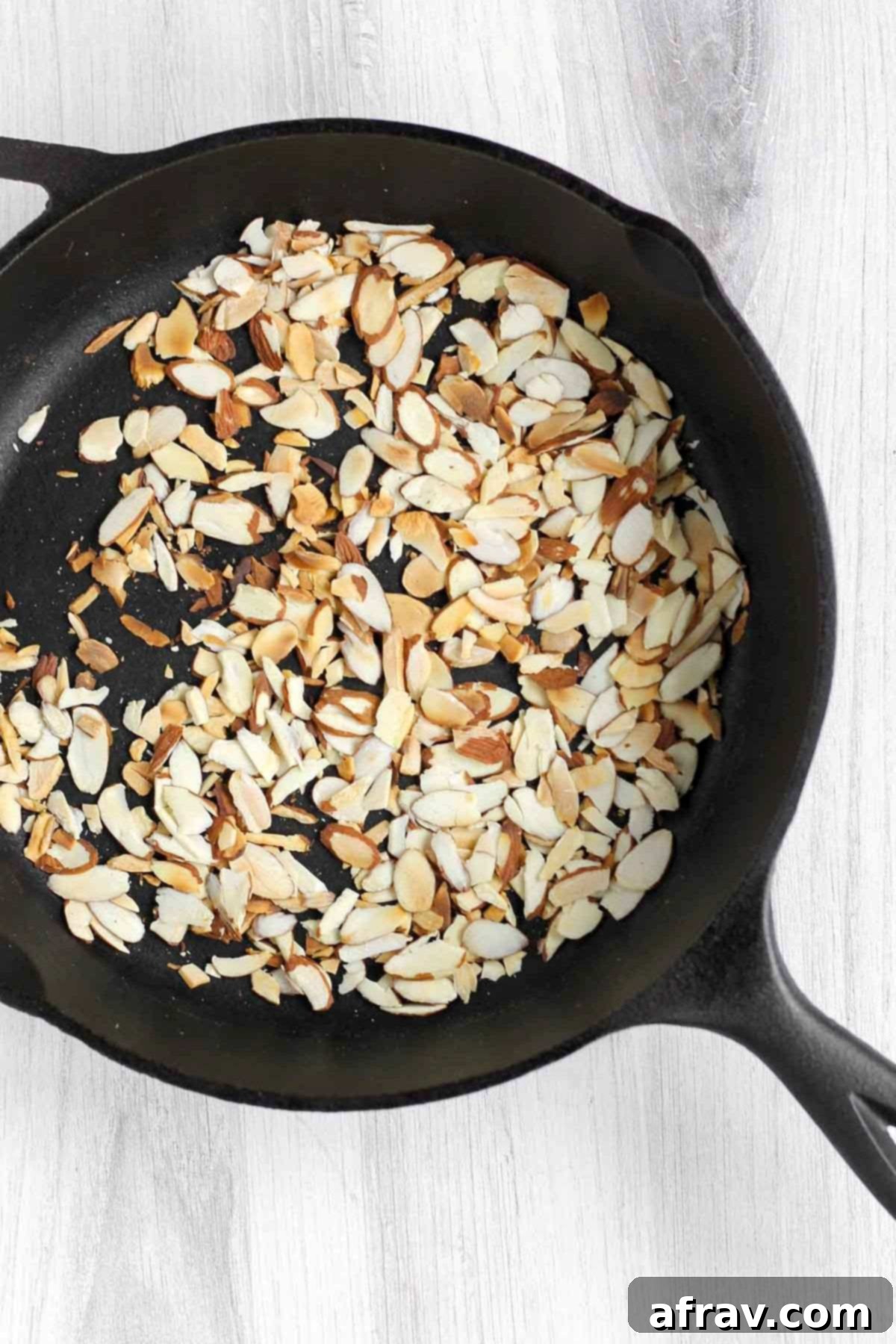 Toasted sliced almonds in a cast iron skillet, golden brown and fragrant.