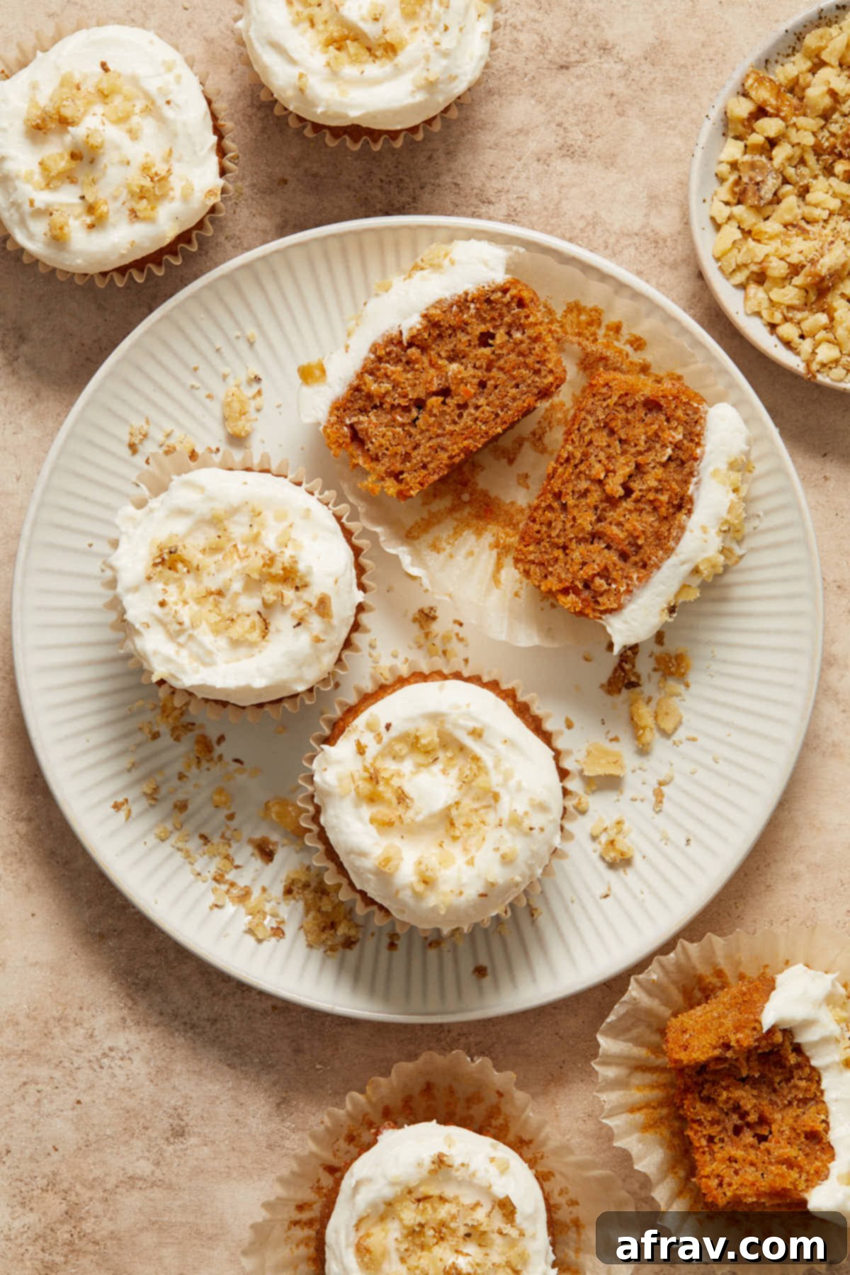 Scrumptious Gluten-Free Carrot Cake Delights 11 Beautifully frosted gluten-free carrot cake cupcakes arranged on a plate, with one cupcake cut in half to show its moist interior.