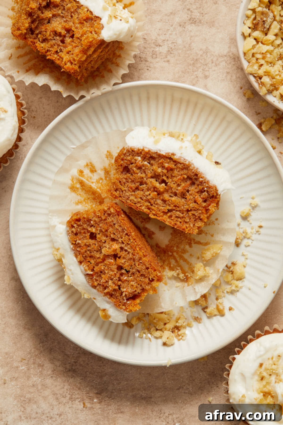 Scrumptious Gluten-Free Carrot Cake Delights 12 A close-up of a gluten-free carrot cake cupcake, freshly cut in half, revealing its moist crumb and visible carrot shreds, on a white plate.