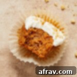 Scrumptious Gluten-Free Carrot Cake Delights 14 Gluten-free carrot cake cupcake on a cupcake liner with a bite taken out.