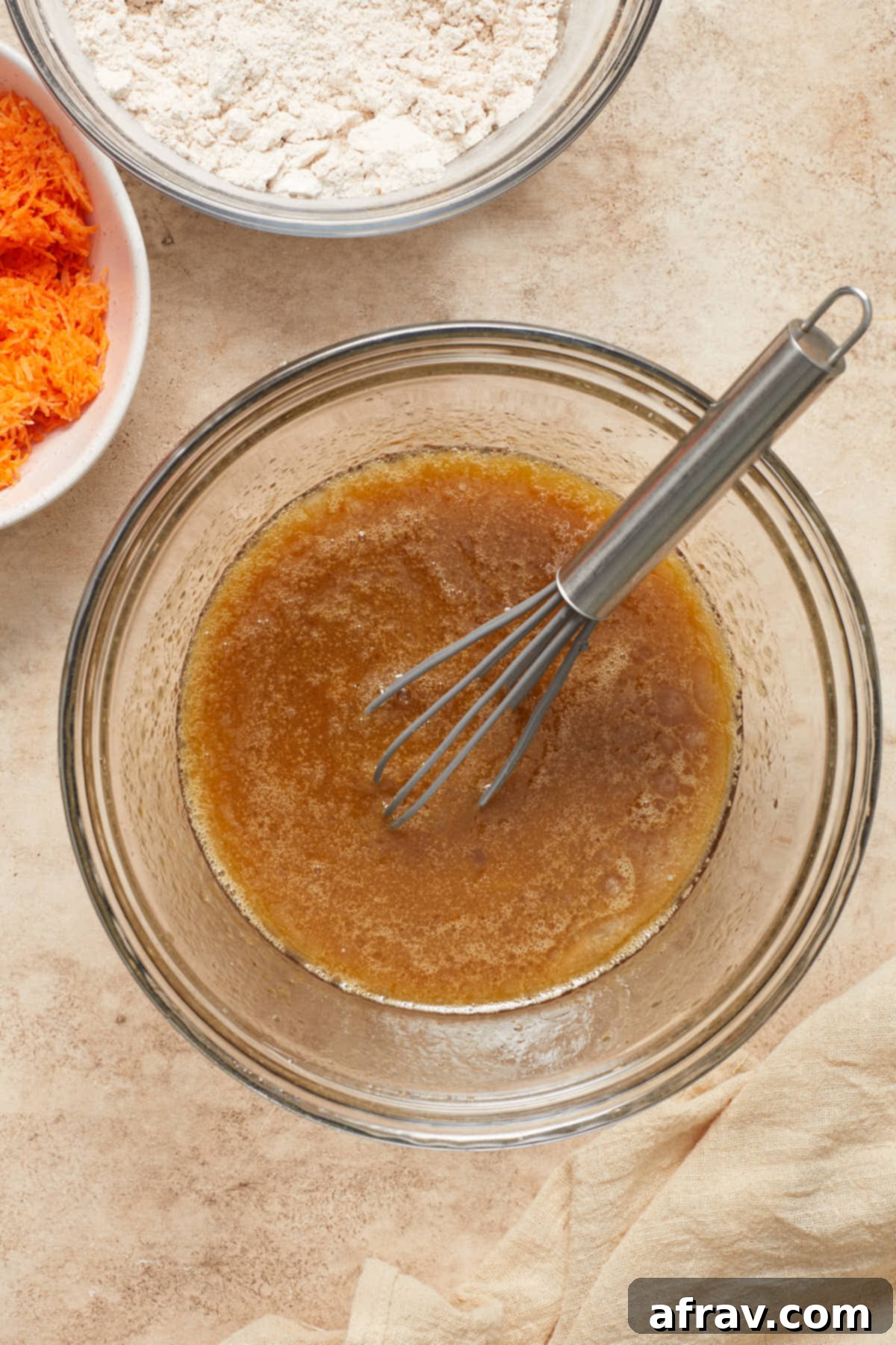 Scrumptious Gluten-Free Carrot Cake Delights 4 Wet ingredients (eggs, sugars, oil, milk, vanilla) whisked together in a clear glass bowl, ready for dry ingredients.