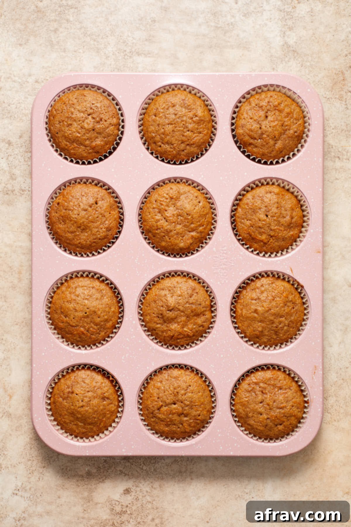 Scrumptious Gluten-Free Carrot Cake Delights 9 Freshly baked gluten-free carrot cake cupcakes cooling in their pan after being removed from the oven.