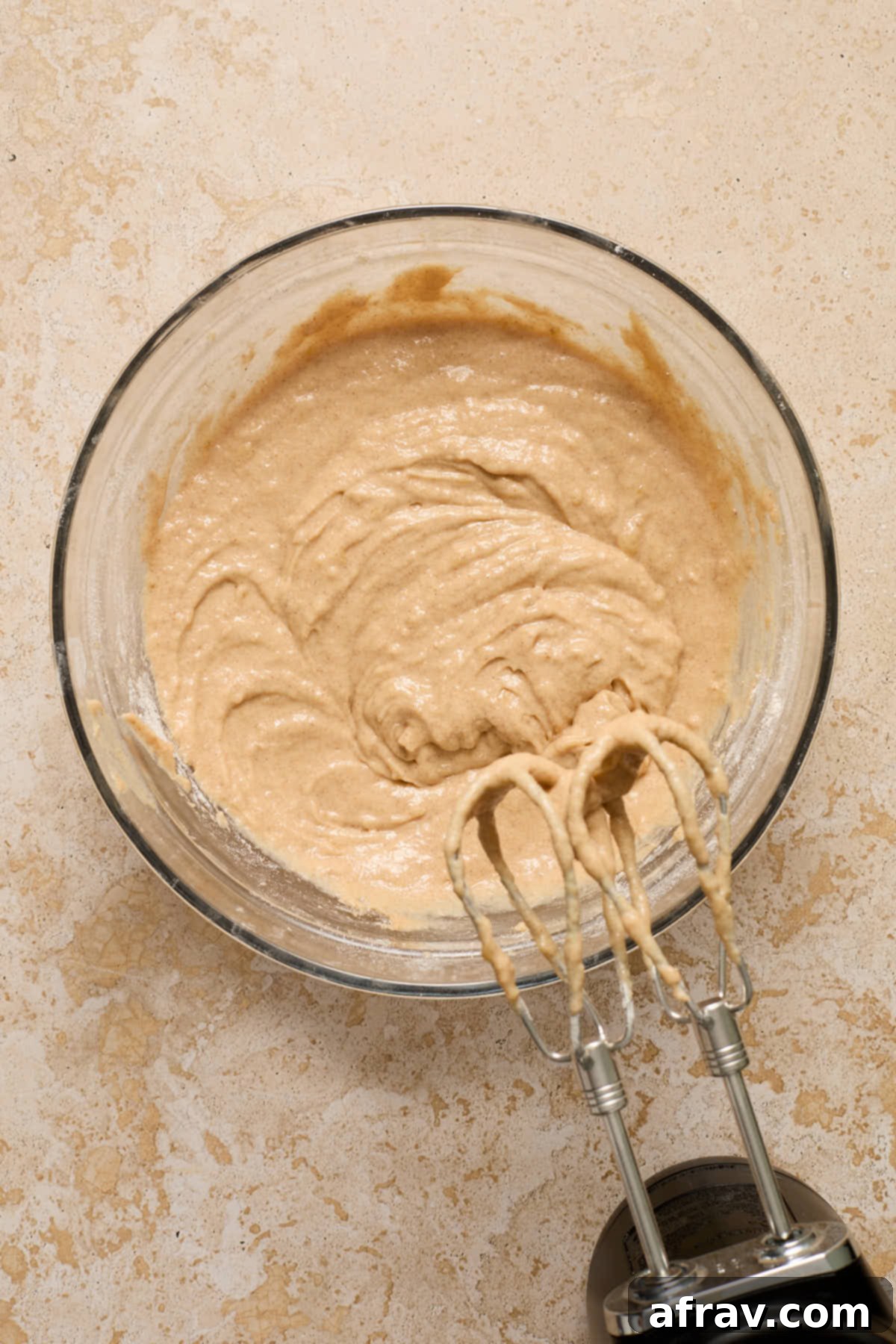 Banana cake batter in a glass bowl, showing the combined wet and dry mixtures.