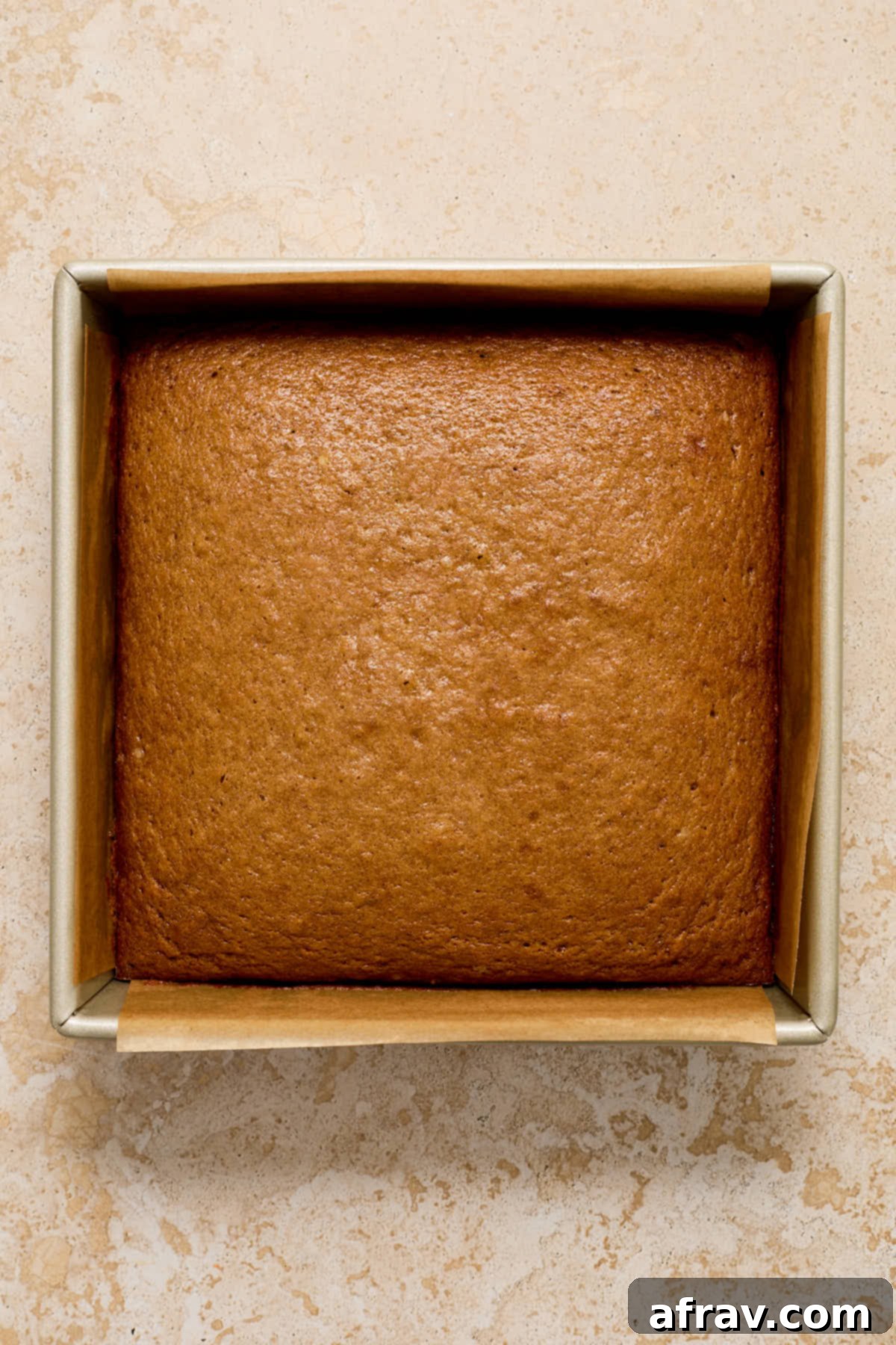 Cake baked up golden brown in a square pan, ready for cooling.
