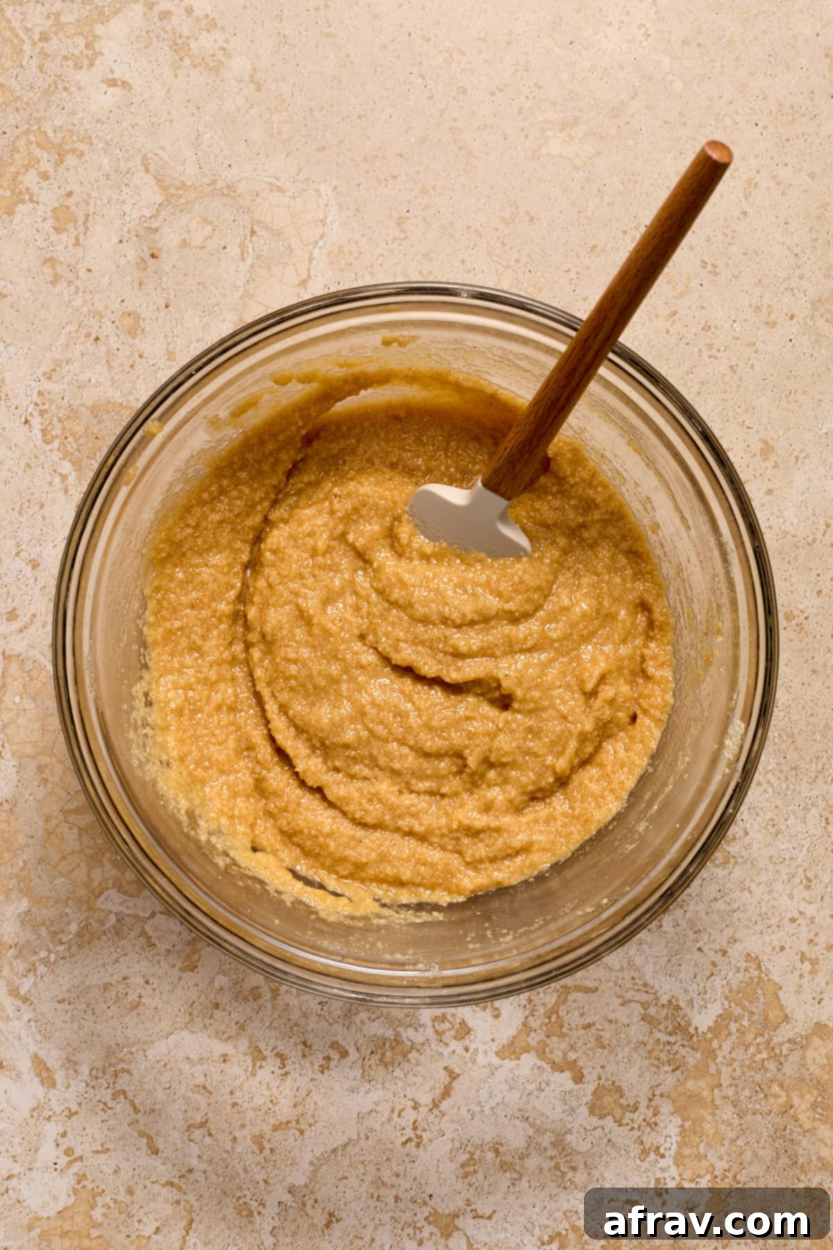 Thick almond flour coffee cake batter stirred together in a glass bowl with a spatula.