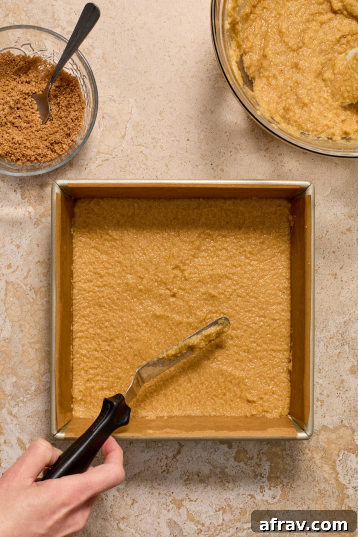 Bottom layer of almond flour coffee cake batter evenly spread in a square baking pan with an offset spatula.