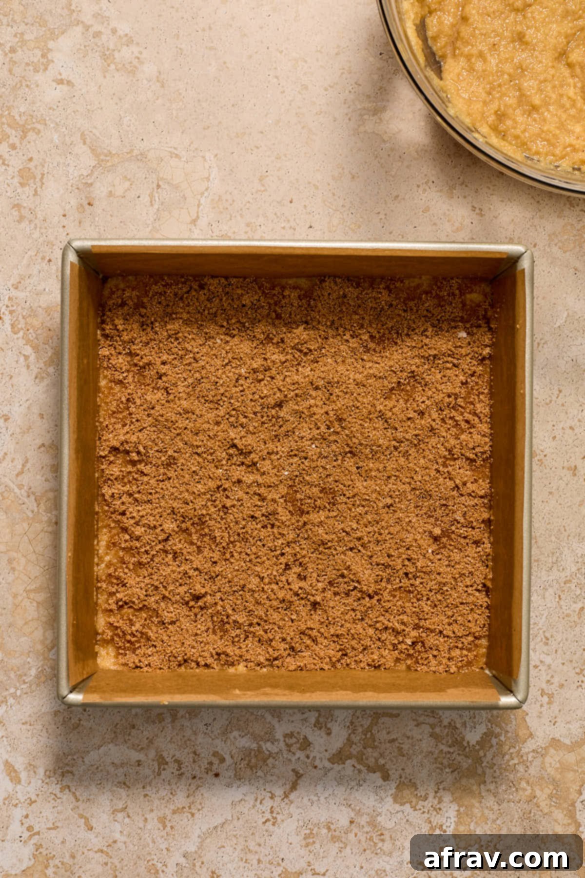 Cinnamon sugar mixture evenly sprinkled over the first layer of coffee cake batter in a square pan.