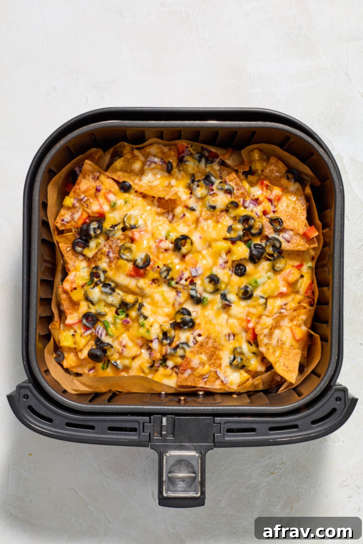 Air fried nachos in the air fryer basket.