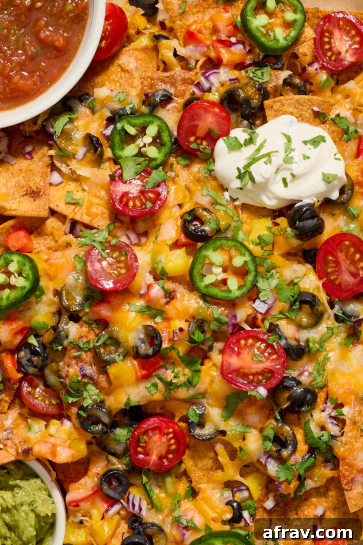 Close up view of the nacho toppings with a dollop of sour cream on top.