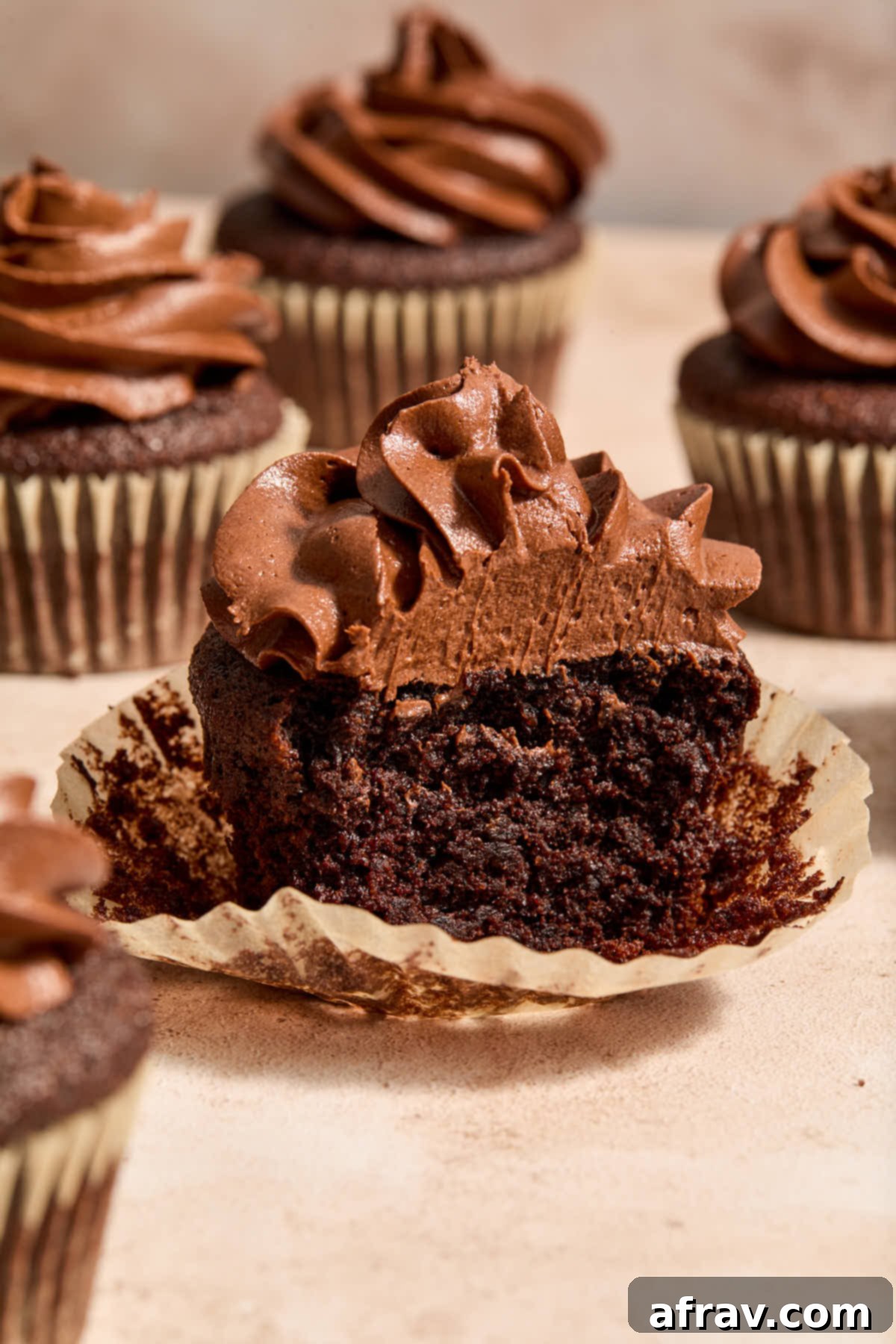 Gluten-Free Almond Flour Chocolate Cupcakes 2 Side view of a chocolate almond flour cupcake on a cupcake wrapper with a bite taken out of it, showcasing its moist texture.