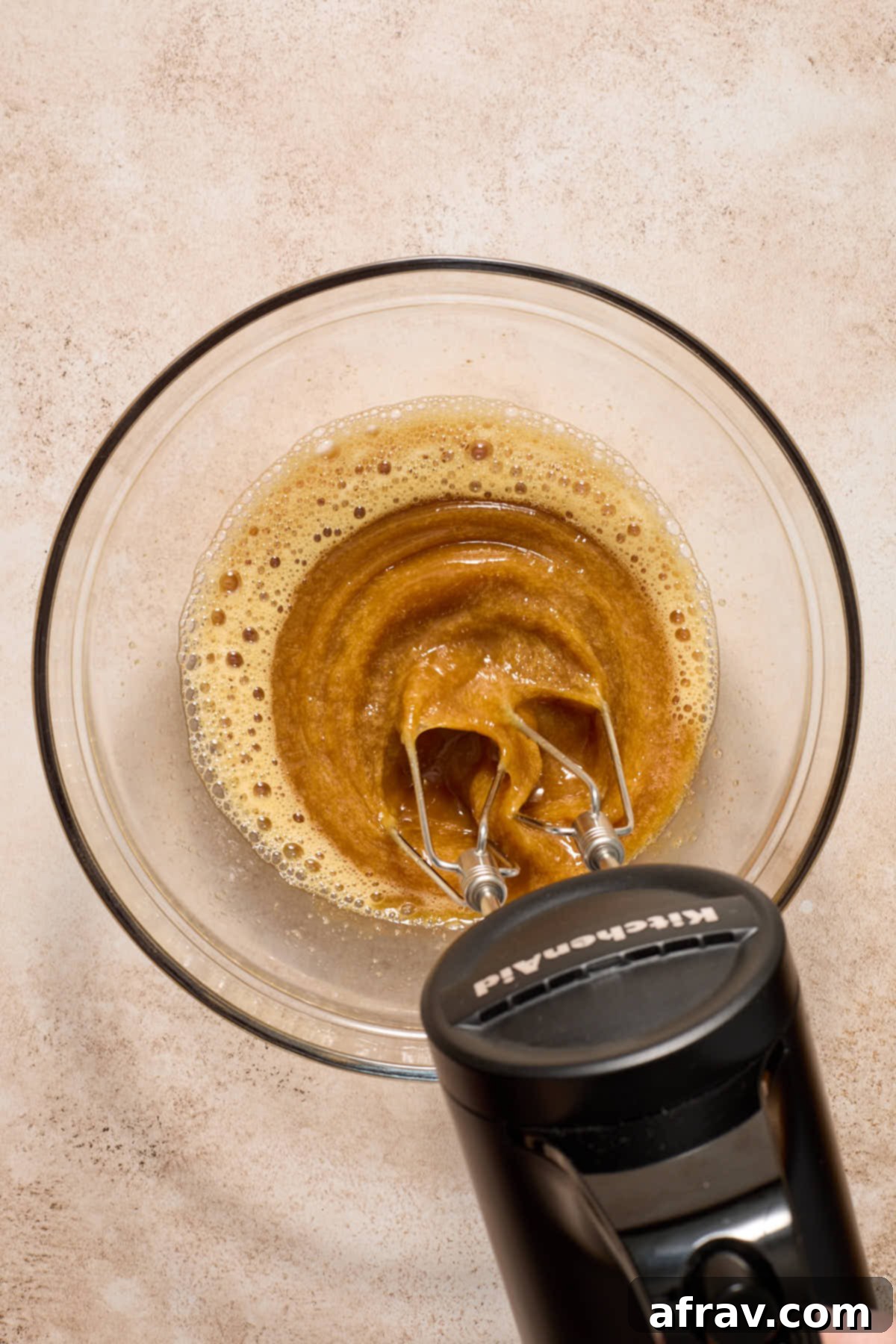 Gluten-Free Almond Flour Chocolate Cupcakes 6 Eggs and brown sugar beaten together in a glass bowl with a hand mixer, showing a frothy mixture.