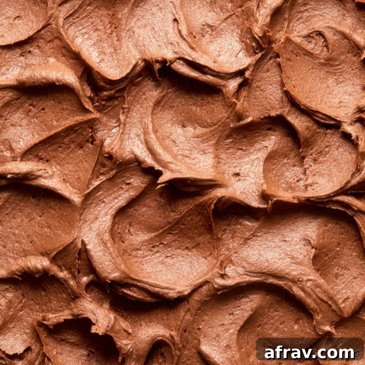 Close up view of swoops and swirls of chocolate peanut butter frosting on top of a cake, showcasing its smooth and irresistible texture.