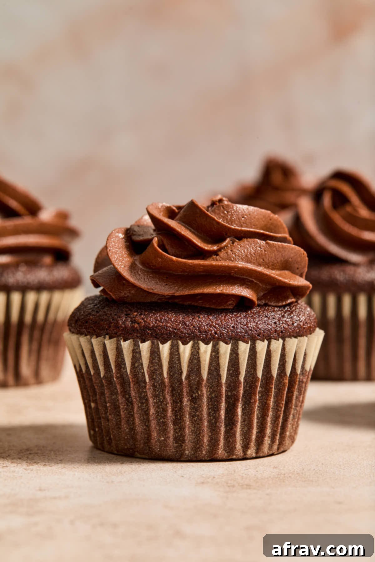 Side view of a chocolate cupcake generously topped with fluffy chocolate peanut butter frosting and a sprinkle of chocolate shavings.