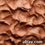 Close up view of swoops and swirls of chocolate peanut butter frosting on top of a cake.