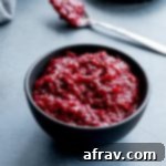 Healthy Cranberry Sauce in a small black bowl on a dark surface, highlighting the rich color and texture.