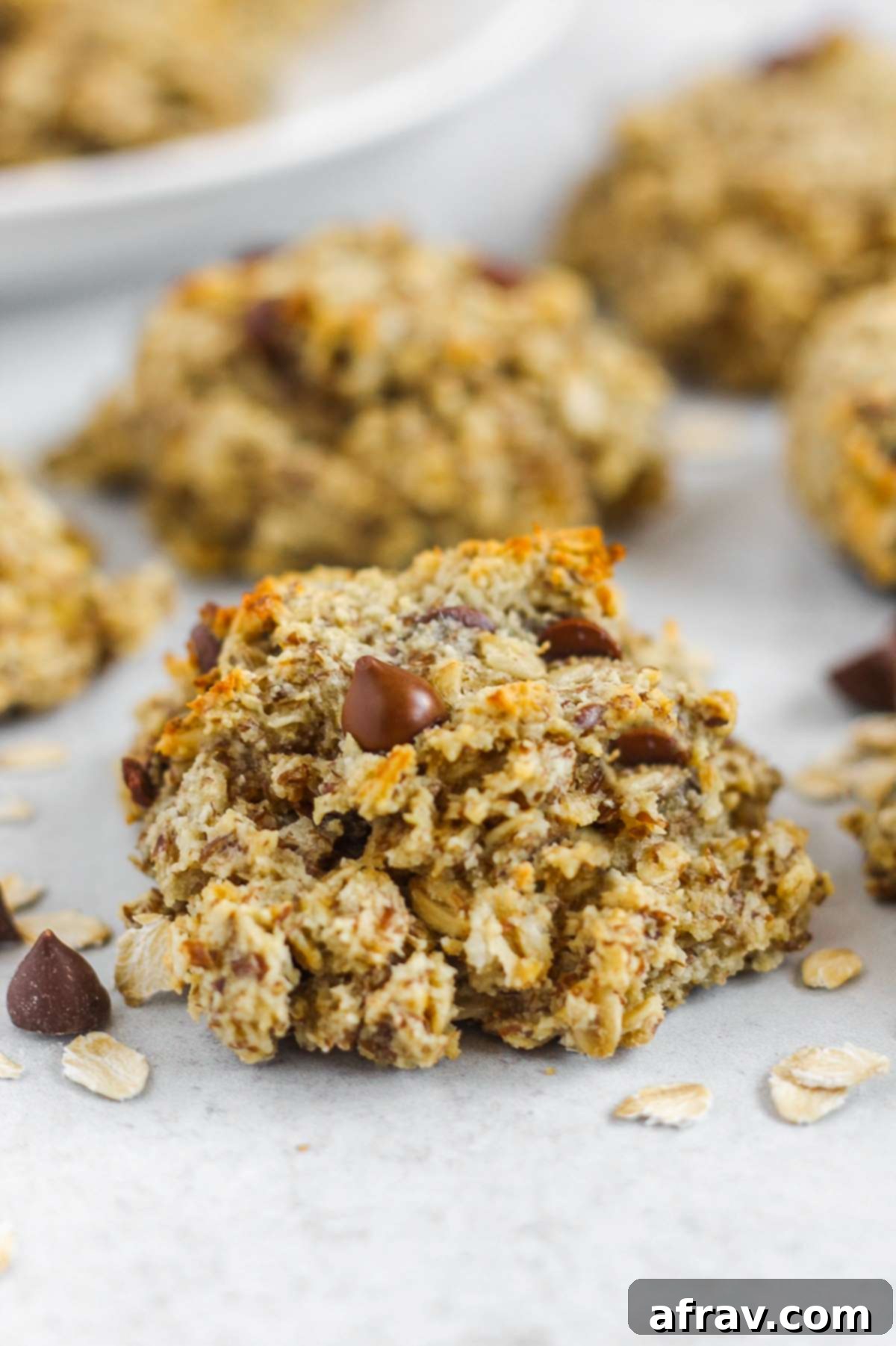 Close-up of a healthy breakfast cookie with visible chocolate chips, sitting on a textured surface.