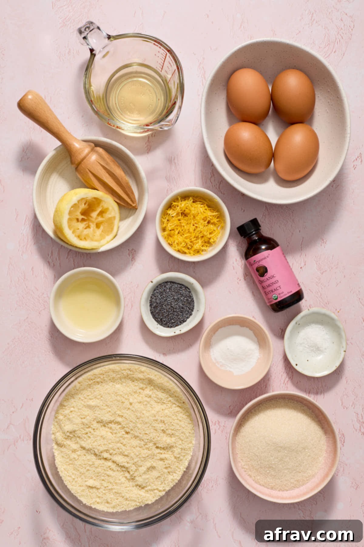 Individually arranged ingredients for almond flour lemon poppy seed cake, including lemons, poppy seeds, and almond flour.