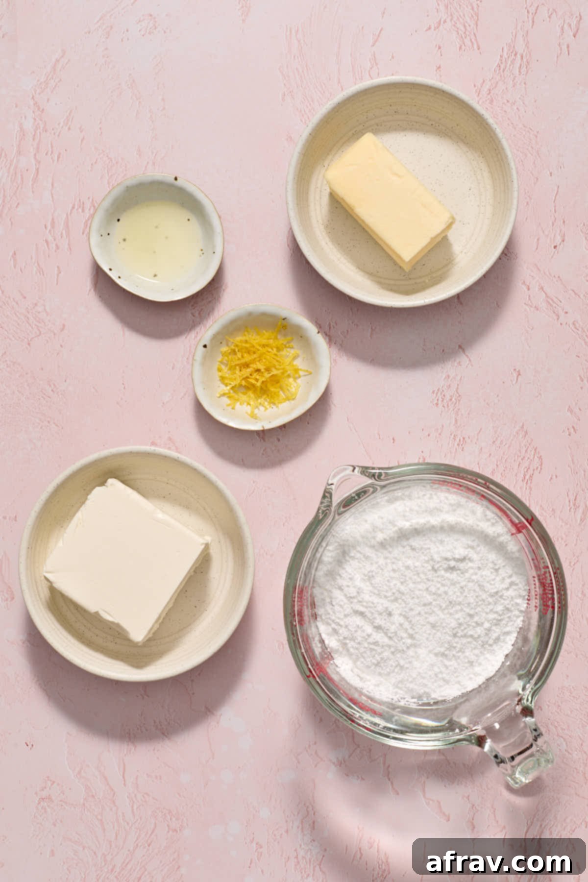 Ingredients for lemon cream cheese frosting, including cream cheese, butter, and powdered sugar, arranged separately.