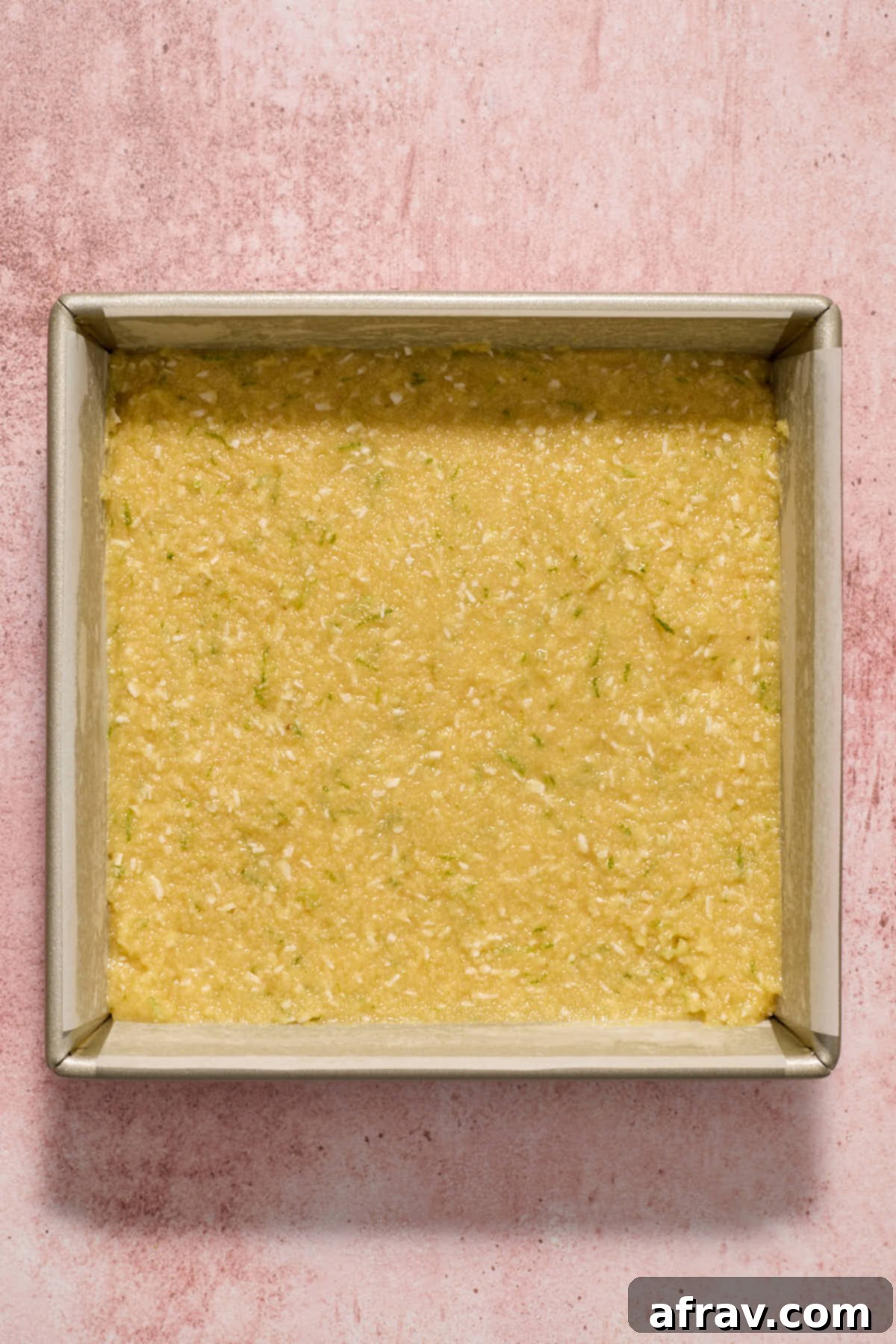 Thick cake batter evenly spread in an 8-inch square baking pan lined with parchment paper.