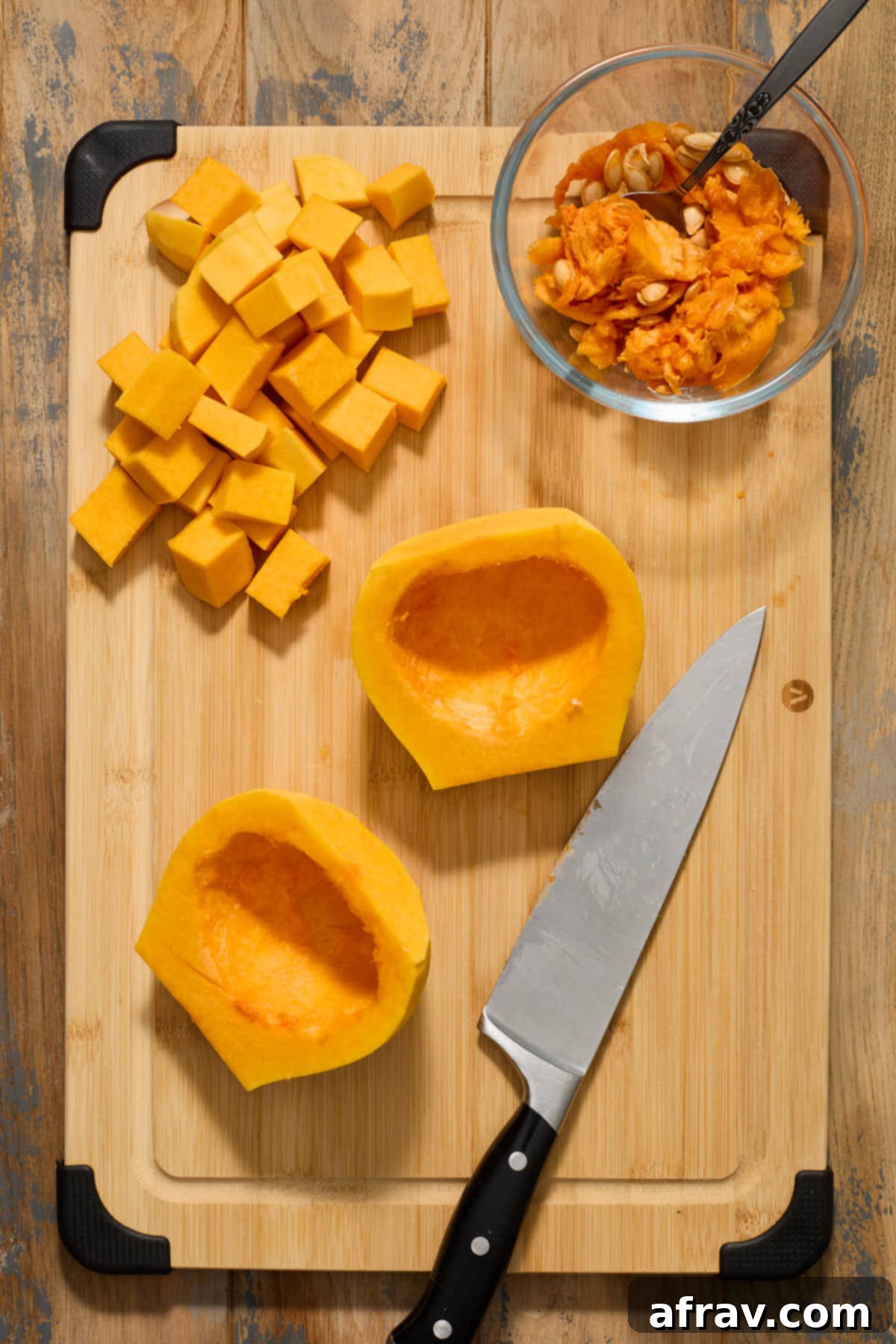 Seeds and stringy pulp neatly scooped out from the butternut squash halves and collected in a small glass bowl, with clean squash halves beside them.