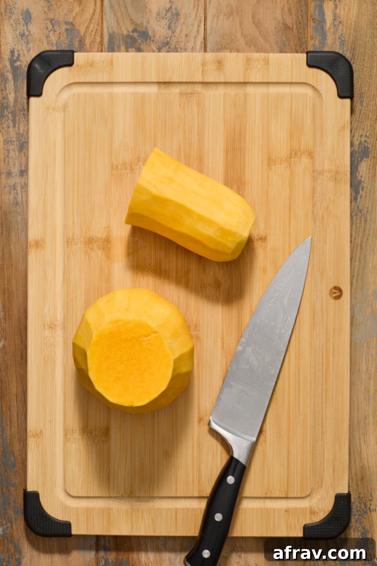 A peeled butternut squash neatly cut into two distinct sections: the solid neck and the bulbous body, separated at their natural junction with a chef's knife.