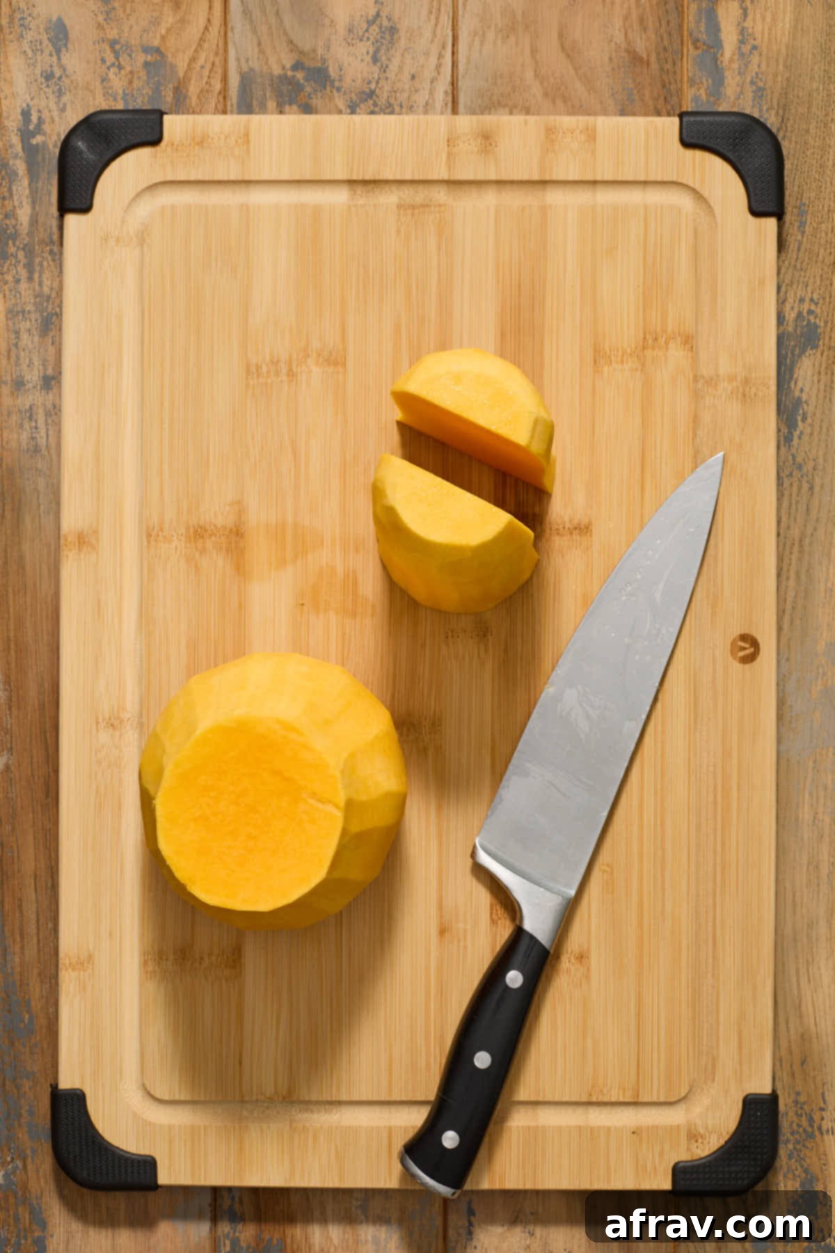 The peeled neck portion of a butternut squash, now cut cleanly in half lengthwise, showing its solid, dense flesh.