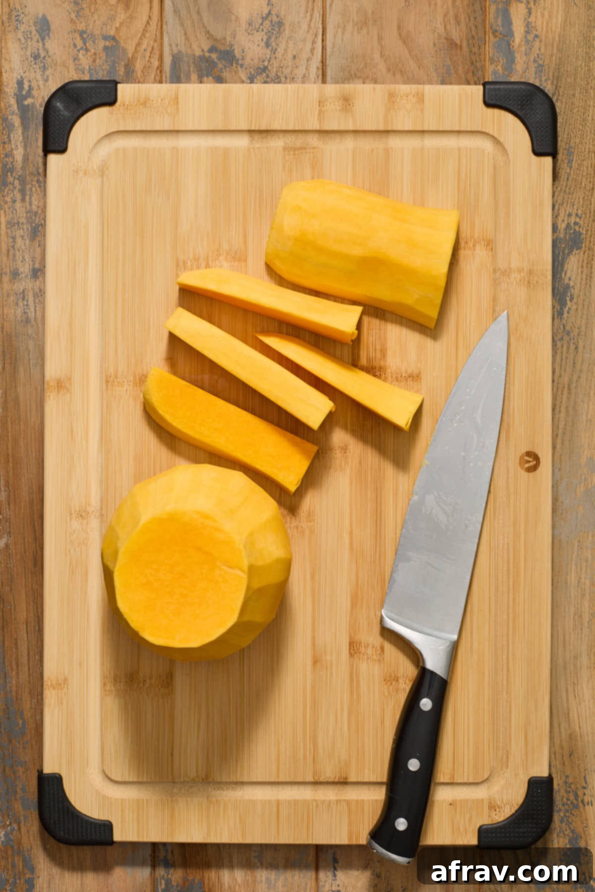 Uniform strips of butternut squash from the neck section arranged on a cutting board, ready for cubing.