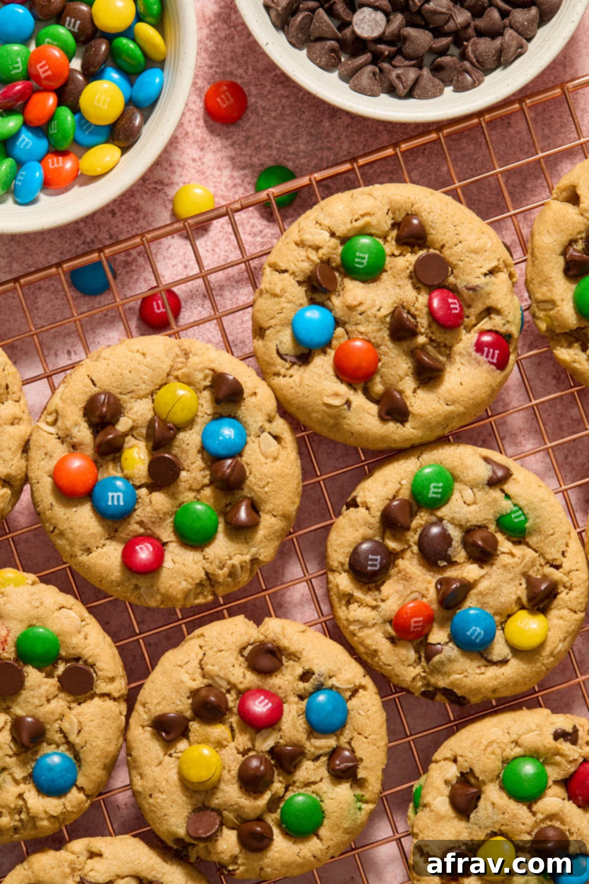 Almond flour monster cookies cooling on a wire rack, with M&Ms and chocolate chips scattered nearby.