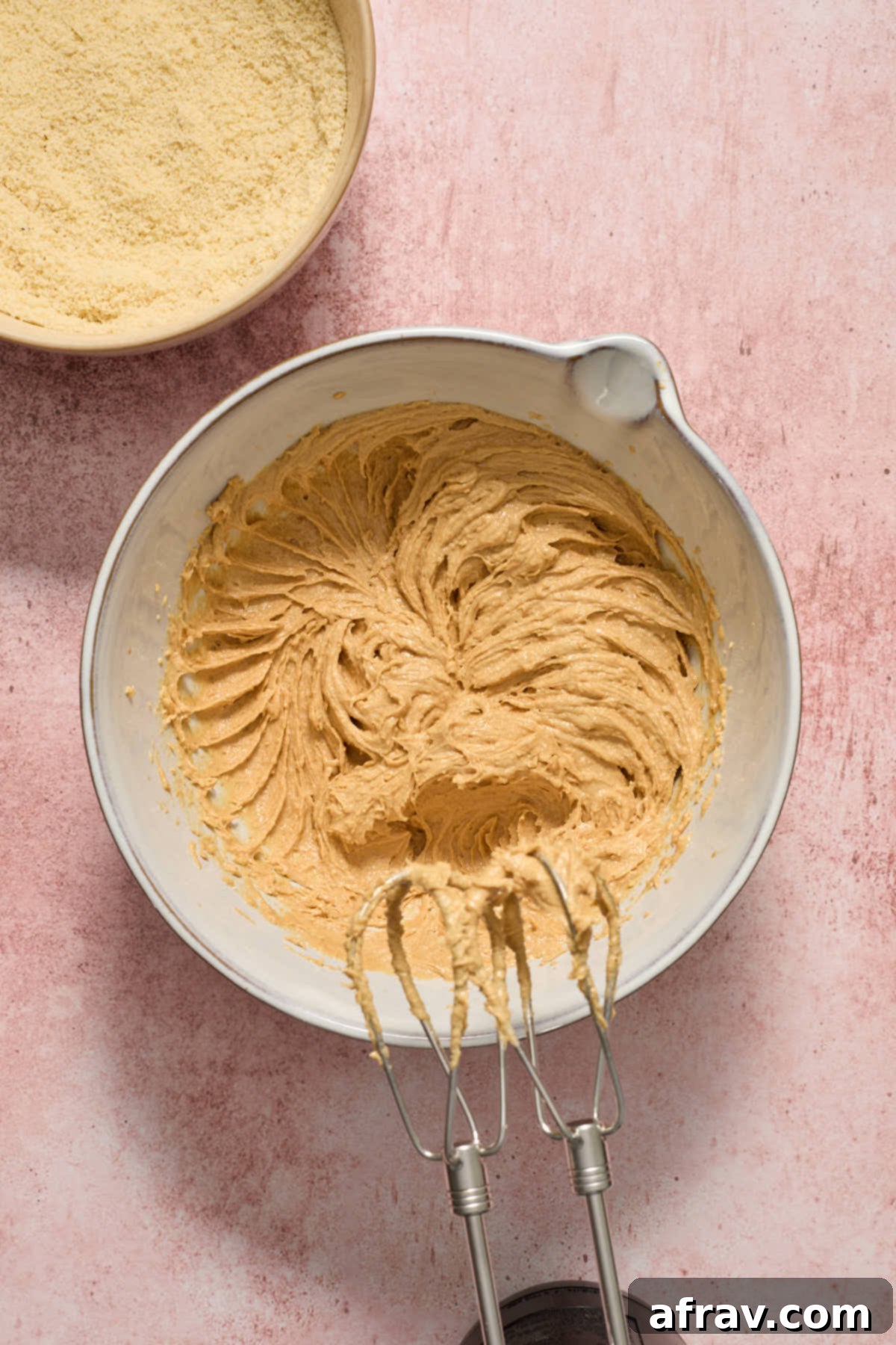 Wet ingredients beaten together in a bowl with a hand mixer, while the dry ingredients wait on the side.