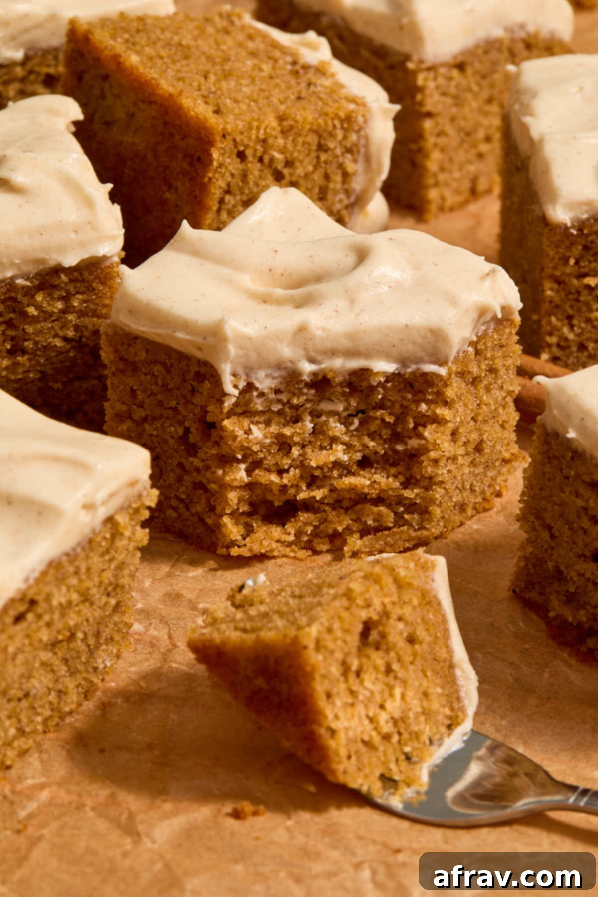 Spiced Almond Flour Pumpkin Cake 2 Front view of a piece of gluten-free almond flour pumpkin cake with a forkful removed, showcasing its moist texture and creamy frosting.