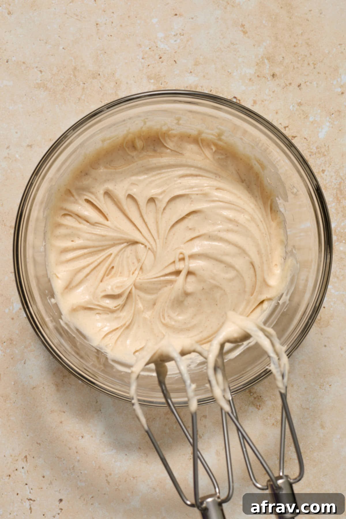 Spiced Almond Flour Pumpkin Cake 11 Cream cheese frosting ingredients beaten together in a glass bowl with an electric mixer.
