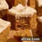 Spiced Almond Flour Pumpkin Cake 15 Piece of almond flour pumpkin cake topped with cream cheese frosting and a forkful removed.