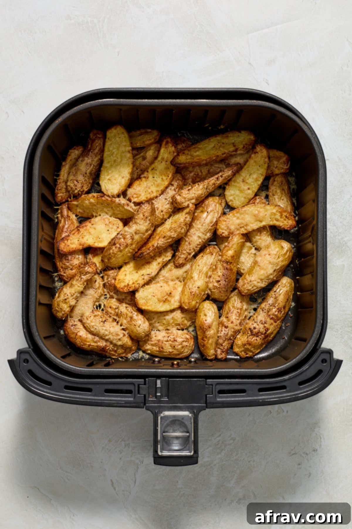 Potatoes in air fryer basket after roasting.