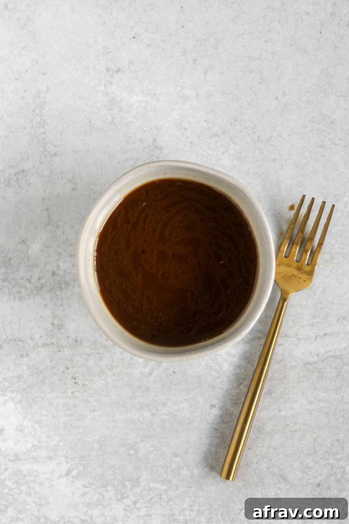 Stir fry sauce in s small bowl with a fork laying on the side.