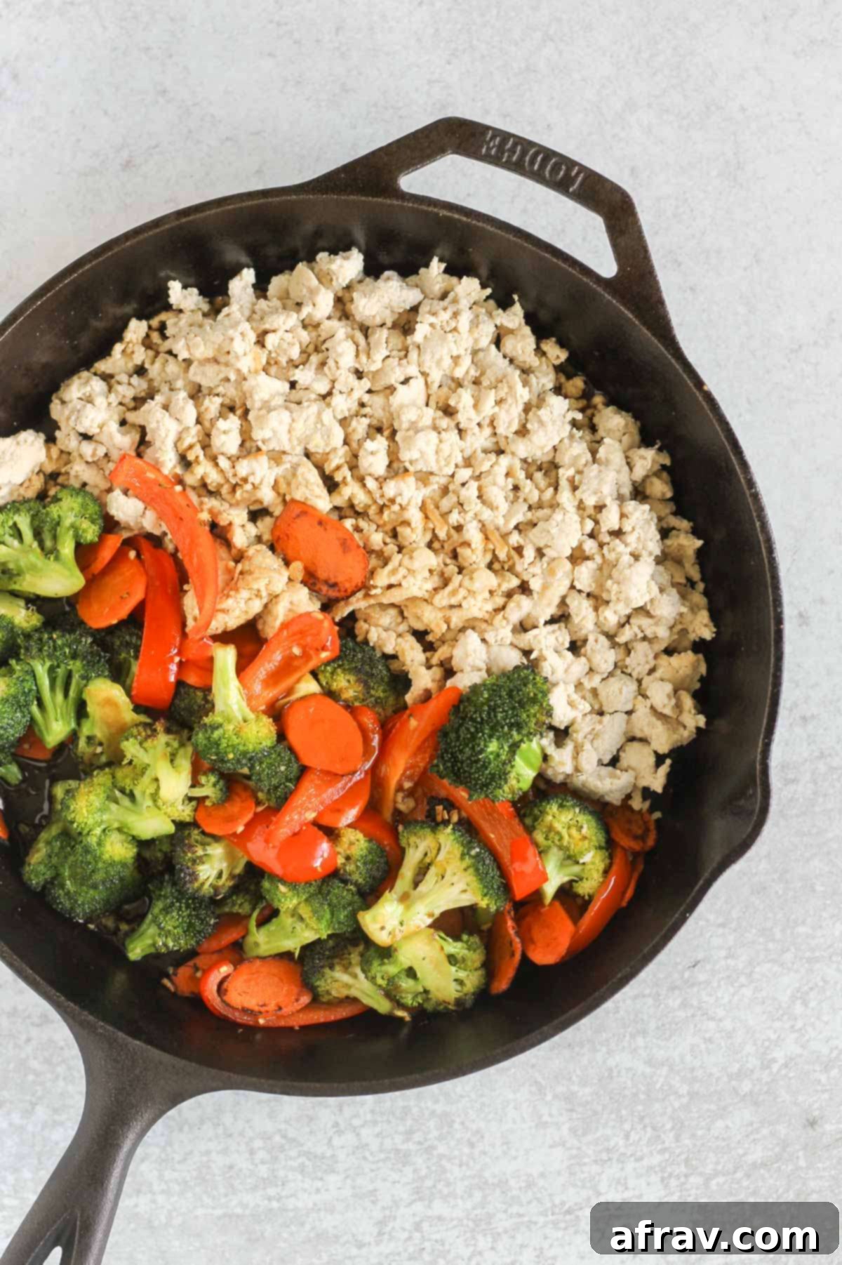 Cooked ground chicken and sauteed veggies in a cast iron skillet.