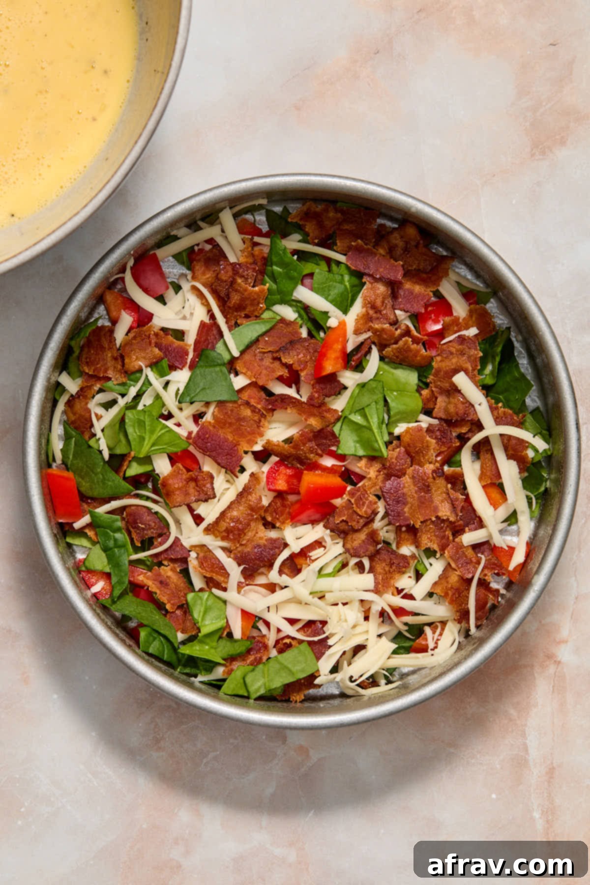 Velvety Air Fryer Frittata with Savory Spinach Bacon and Cheese 5 Spinach, bacon, cheese, pepper and onion added to a 7-inch round pan, ready for the egg mixture.