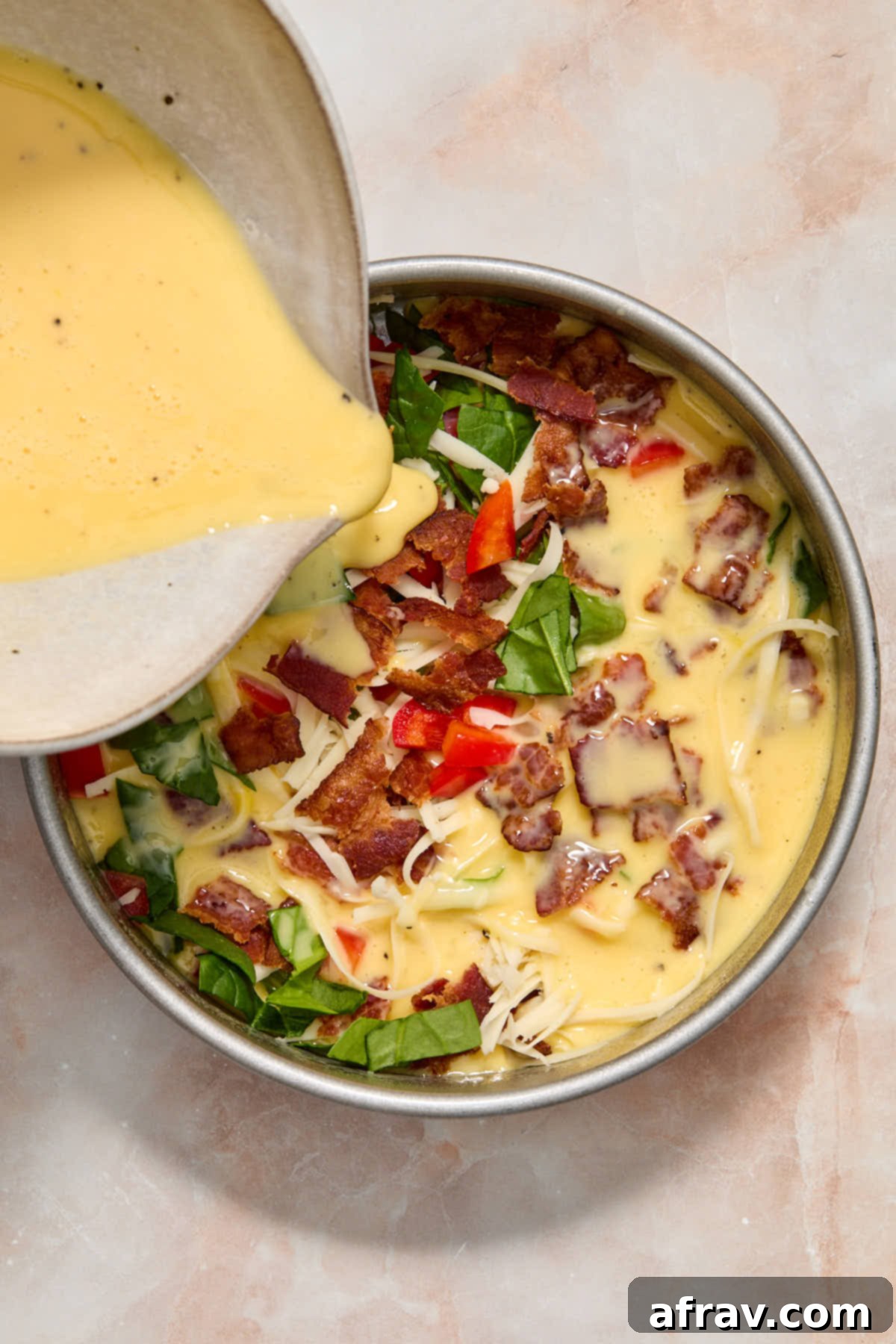 Velvety Air Fryer Frittata with Savory Spinach Bacon and Cheese 6 Pouring egg mixture over the frittata filling in the pan.
