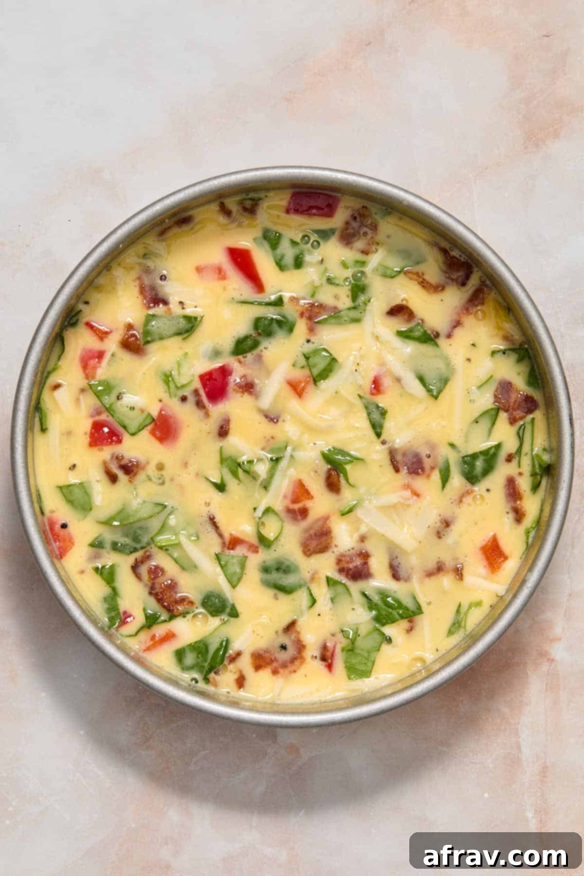 Velvety Air Fryer Frittata with Savory Spinach Bacon and Cheese 7 Egg mixture fully poured over filling in a round pan, ready for the air fryer.