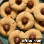 Overhead view of almond flour peanut butter blossoms with chocolate kisses arranged on a green plate, highlighting their perfect form.