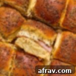 Close up of air fryer ham and cheese sliders with one turned on its side to show the ham and cheese filling.