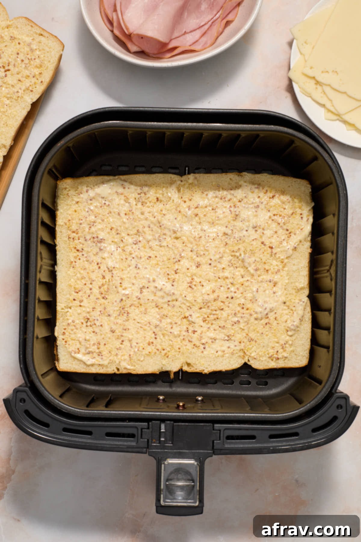 Bottom half of sweet rolls topped with mayo/mustard mixture and placed in the bottom of the air fryer basket.