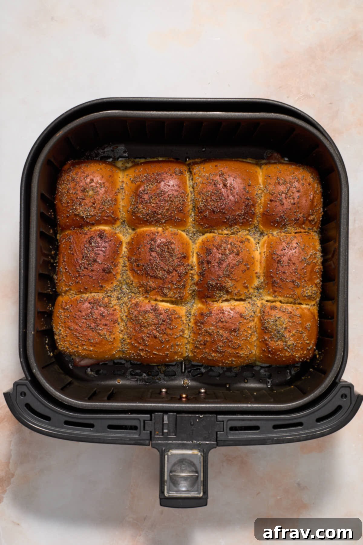 Air fried ham and cheese sliders in the air fryer basket.
