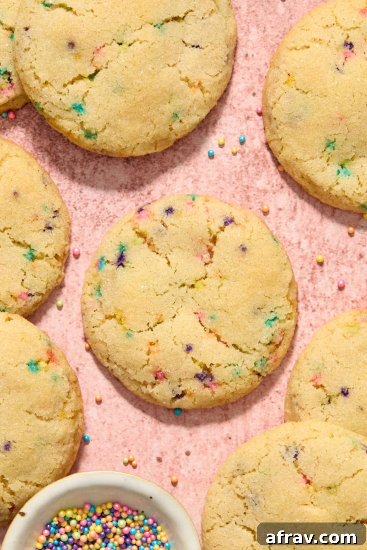 Sugar cookies with sprinkles arranged on a pink surface. These are delicious gluten-free almond flour sugar cookies, perfect for any occasion.