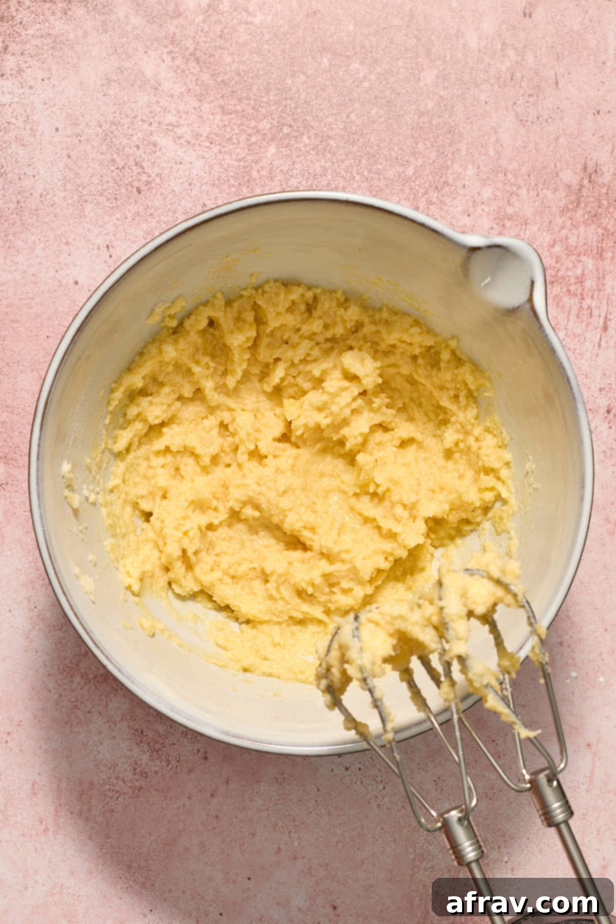 Wet mixture of butter, sugar, egg, and vanilla extract beaten together until fully combined and smooth in a large white bowl.