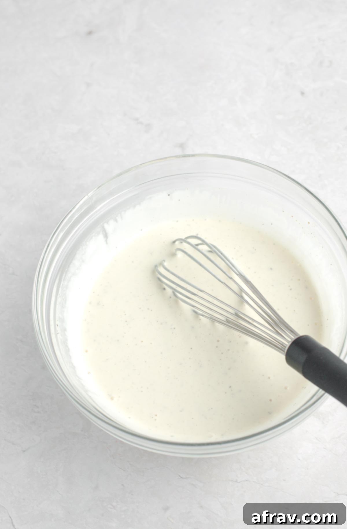Chicken salad dressing in a bowl, being whisked to combine.