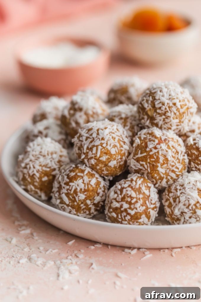 Wholesome Coconut Apricot Energy Bites 6 Side view of coconut apricot balls piled on a white plate.