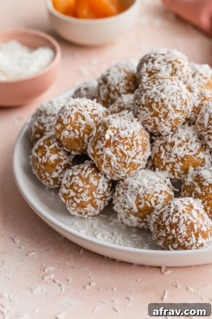 Wholesome Coconut Apricot Energy Bites 7 Close up of apricot balls covered in coconut and piled on a white plate.