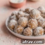 Wholesome Coconut Apricot Energy Bites 8 Side view of coconut apricot balls piled on a white plate.