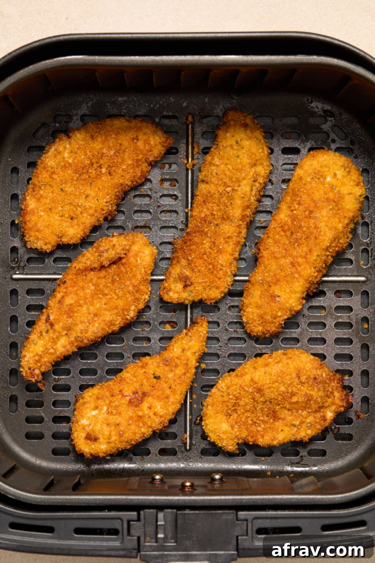 Air fried chicken strips in the air fryer basket.